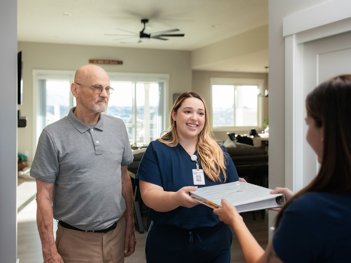Two nurses review a claims binder with a patient